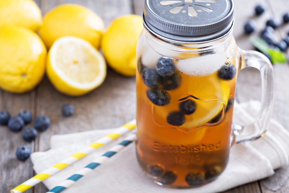 FCOM - Ice tea in mason jar mug with lemon and blueberries refreshing in hot summer day